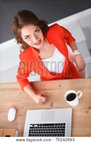 Attractive woman sitting at desk in office, working with laptop