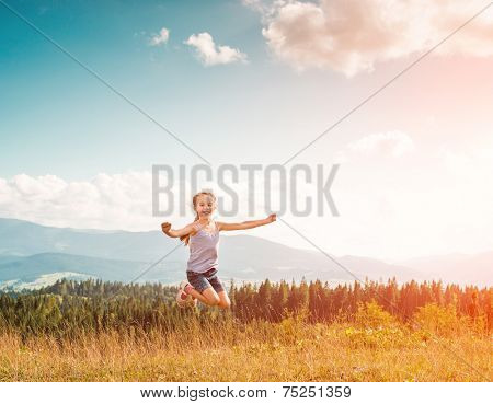 little girl runs through a beautiful meadow in the mountains. back view