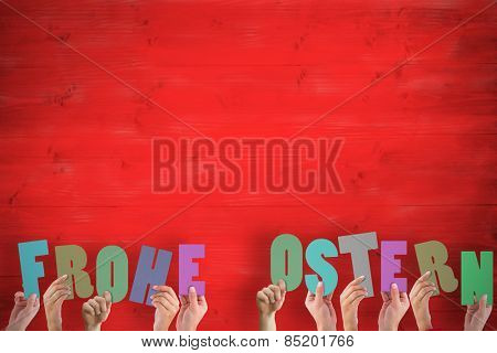 Hands holding up frohe ostern against red wooden planks