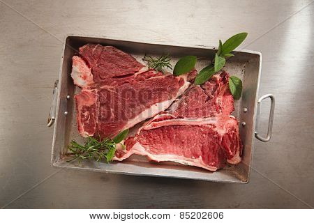 beef steak t-bone with vintage meat fork on metal backdrop