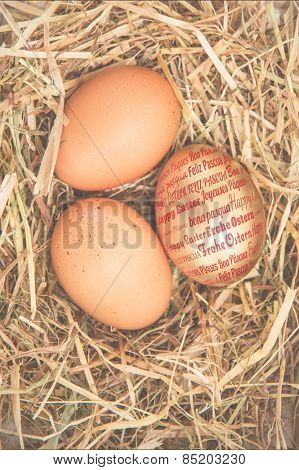 Happy easter in different languages against gold egg in the straw with others