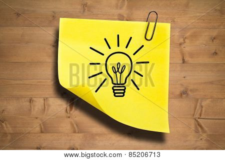 Light bulb against sticky note with grey paperclip