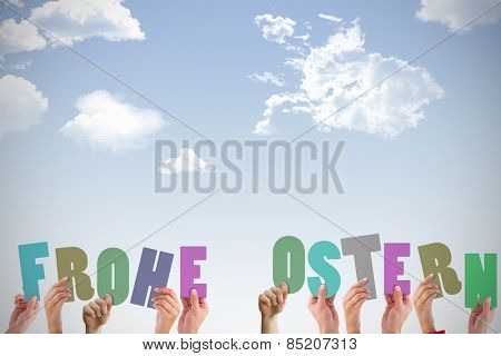 Hands holding up frohe ostern against blue sky