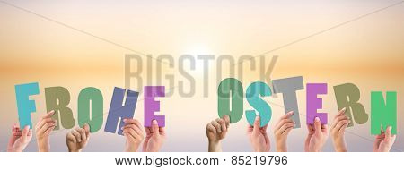 Hands holding up frohe ostern against purple and orange sky