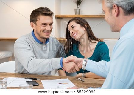 Happy young couple shaking hands for a financial agreement