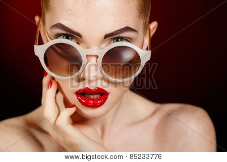 Beautiful young model with red lips and red manicure on black background