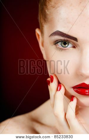 Beautiful young model with red lips and red manicure on black background