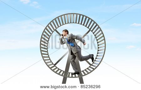 Young businessman running in huge hamster wheel