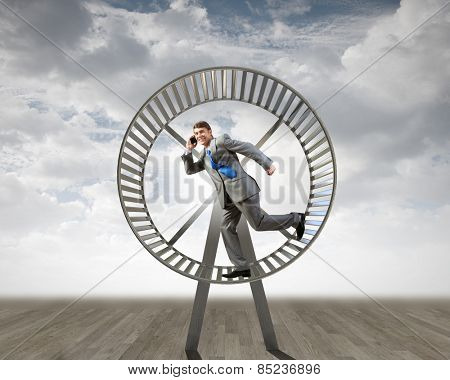 Young businessman running in huge hamster wheel