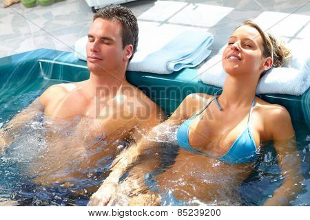 Young couple relaxing in hot tub. Summer vacation.