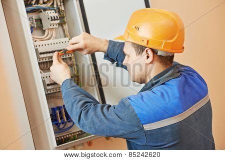 Young adult electrician builder engineer screwing equipment in fuse box