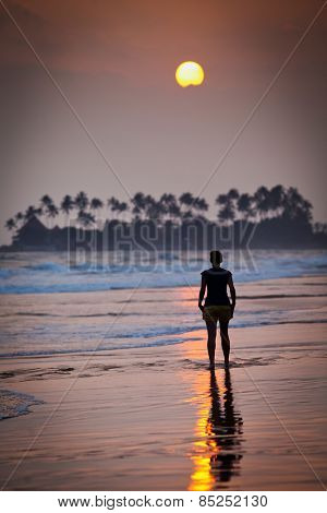 Woman walking on beach at sunset