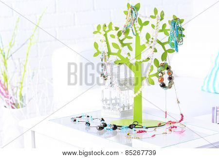 Decorative stand with jewelry and bijouterie on table in room