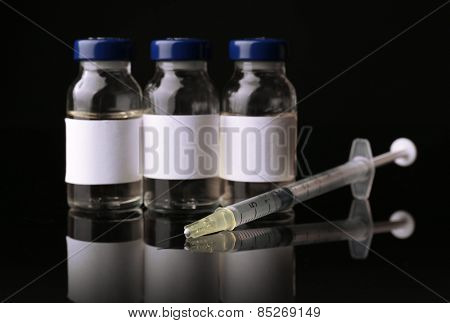 Ampules with syringe on black background