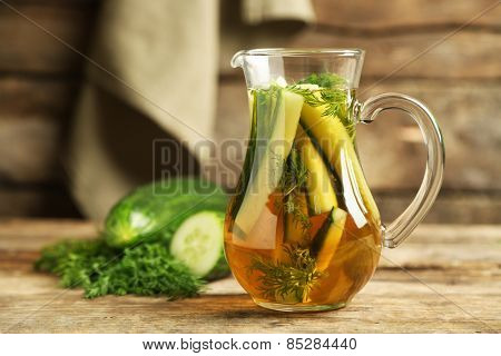 Glass ewer with fresh organic cucumber water on wooden table