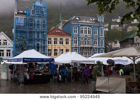 BERGEN, NORWAY - JUN 10 2015 : Shoppers struggle to stay dry at a rainy outdoor market.