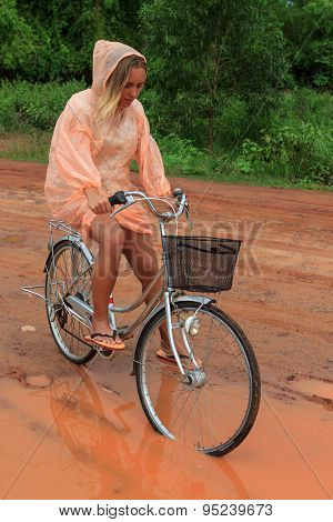 Young Woman Riding Bicycle In Tropical Summer Rain