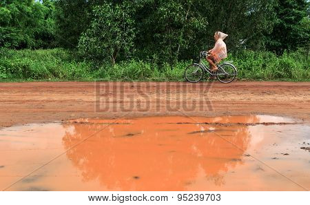 Young Woman Riding Bicycle In Tropical Summer Rain
