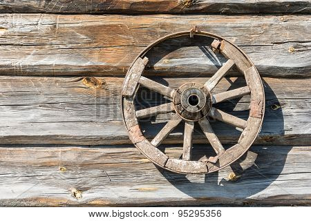 Wooden Wheel On The Log Wall.