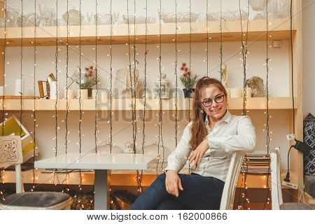 Young business woman sits at the table in own cafe.