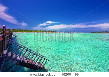 Stairs leading to tropical lagoon on Maldives island.