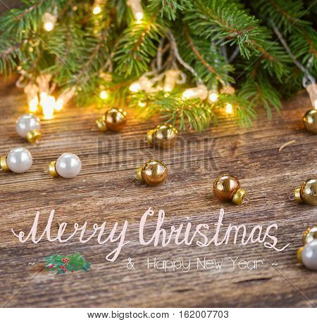 christmas background - wooden table with defocused lights and glass decorationd with merry christmas greetings