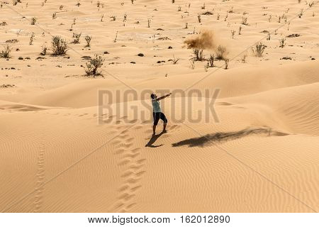 Man tourist in desert rub al khali in Oman throwing sand 4
