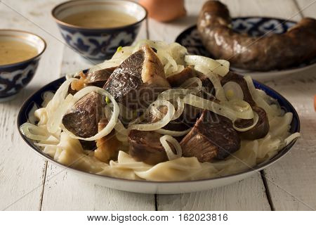 National Kazakh dish - Beshbarmak prepared with meat and pasta on the white wooden table