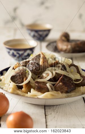 National Kazakh dish - Beshbarmak prepared with meat and pasta on the white wooden table