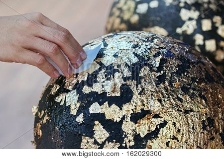 Gilding Gold Leaf To Round Stones Embedded For Worship Buddha.