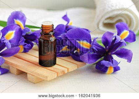 Aroma oil dropper bottle, bright fresh blue flowers, towel. Botanical beauty treatment.