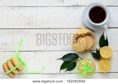 Shortbread lemon flavored cookies: a broken and connected green ribbon for a gift. Fresh lemon on a white wooden background. The top view