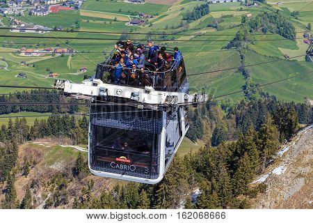 Mt. Stanserhorn, Switzerland - 7 May, 2016: people in a gondola of the Stanserhorn Cabrio cable car approaching the station on the top of the mountain. Stanserhorn Cabrio is the the world's first double deck open top cable car.