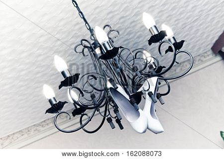 Bride white shoes hung on a chandelier