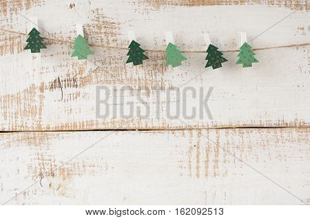 Wooden clothespins decorated Christmas trees hitched to the rope. Free space for text.