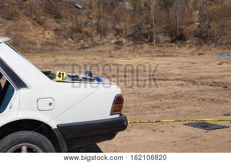 white wrecked car from car bomb with evidence marker and forensic search tool with police line background in post blast training course