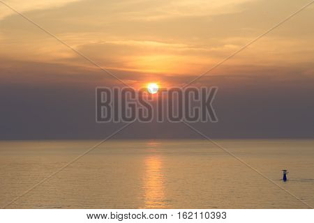 sunrise over calm sea and silhouette lighthouse in morning with warm tone for background