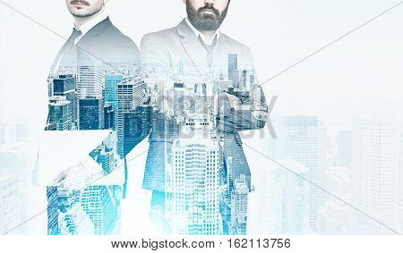 Portrait of two businessmen. One is standing with his arms crossed the second is holding a laptop. Cityscape is at the foreground. Film effect. Toned image. Mock up. Double exposure