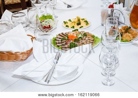 Cutlery and cold cuts served on a festive table in restaurant
