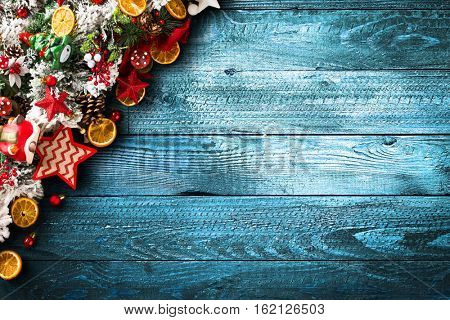 Merry Christmas Frame with green pine, colorful baubles, knots with berries,stars, orangesand other seasonal stuff over an old wooden aged background