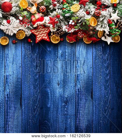 Merry Christmas Frame with green pine, colorful baubles, knots with berries,stars, orangesand other seasonal stuff over an old wooden aged background