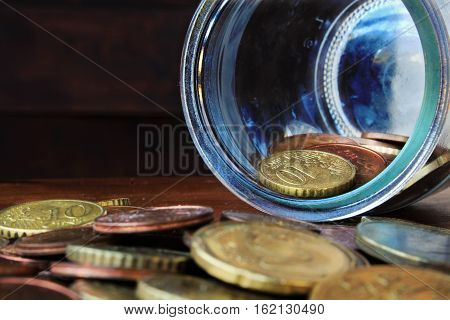 coins in the glass bottle on the wood background
