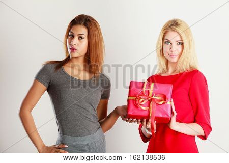 Occasions gifts people concept. Beautiful women blonde caucasian girl and  with red gift box on gray