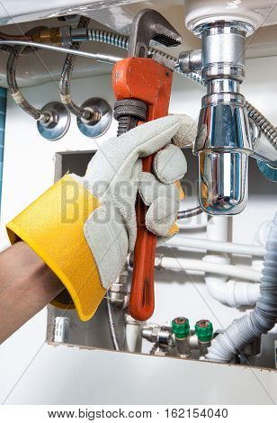 Plumbing work and sanitary engineering repairing a pipe under a sink. Sanitary works. Plumber repairing
