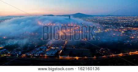 Early morning fog over the rising city of Queretaro Mexico. The aqueduct of Queretaro, is currently building a monumental seventy four arches reaching an average height of twenty eight meters.