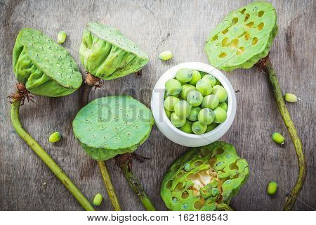 Fresh lotus seeds in vase and on wooden table background.