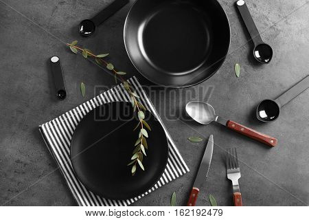 Black plates and cutlery on gray background,top view