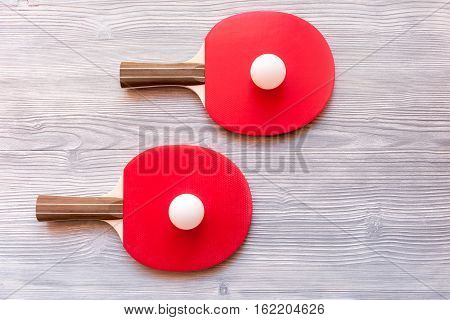 Red racket for ping pong ball on gray wooden background top view