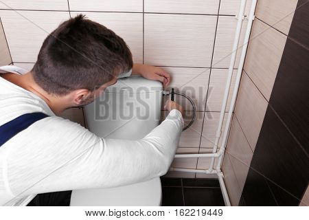 Plumber fixing water hose on toilet cistern