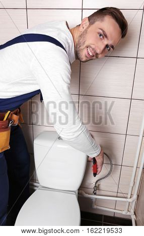 Plumber fixing water hose on toilet cistern